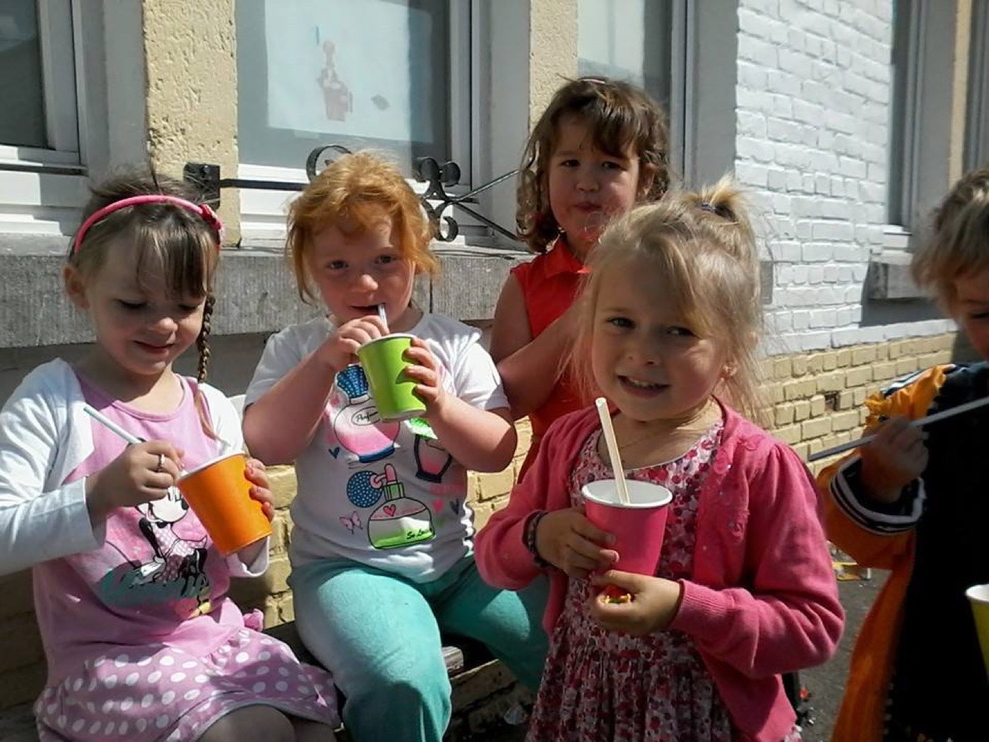 Des enfants de maternelle boivent leur collation dans la cour